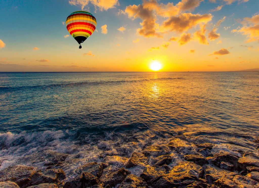 Luchtballon boven zee bij zonsondergang